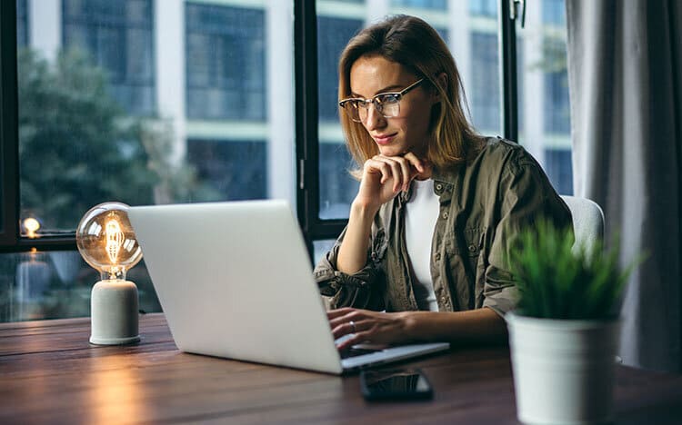 Professional business woman working on laptop computer in modern office setting for HCL Workload Automation