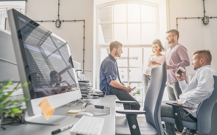 Development team collaborating in modern office with code visualization on monitor demonstrating OpenAPI scanning capabilities