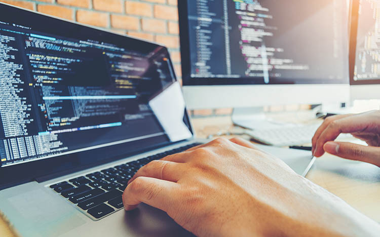 Software developer working on multiple screens showing programming interfaces and development environment tools